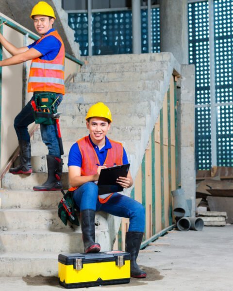 Indonesian builder or craftsman with hardhats, checklist and a bubble level controlling or checking a walls of a tower building or construction site Indonesia Construction Safety Standards.