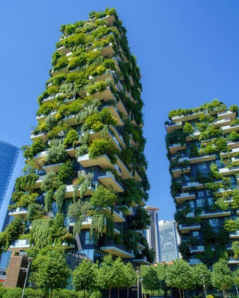 Two tall buildings with greenery climbing their walls, illustrating a sustainable approach to urban living.