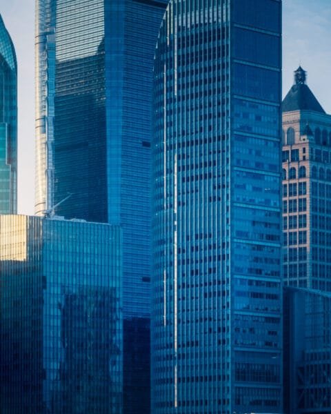 Sunrise peeking between modern skyscrapers in a dense urban cityscape to represent Public-Private Partnerships Indonesia.