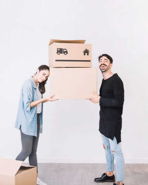 Indonesia Urbanization and Construction Growth represent by two people carrying cardboard boxes in a room with more boxes on the floor.