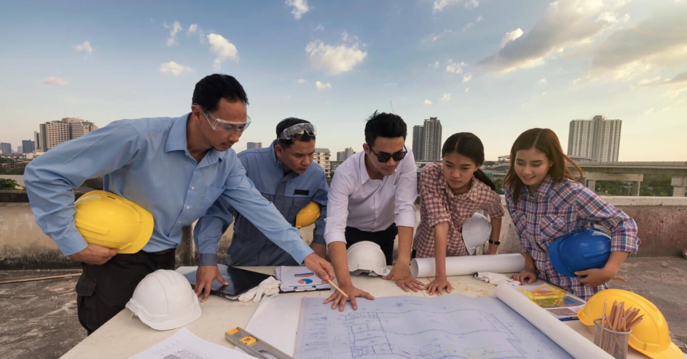 Indonesia Construction Workforce Development: Group of construction workers discussing blueprints on a rooftop.