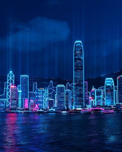 Indonesia Smart City Innovations: Neon-lit skyline of Hong Kong's Victoria Harbour at night with cyberpunk aesthetics.