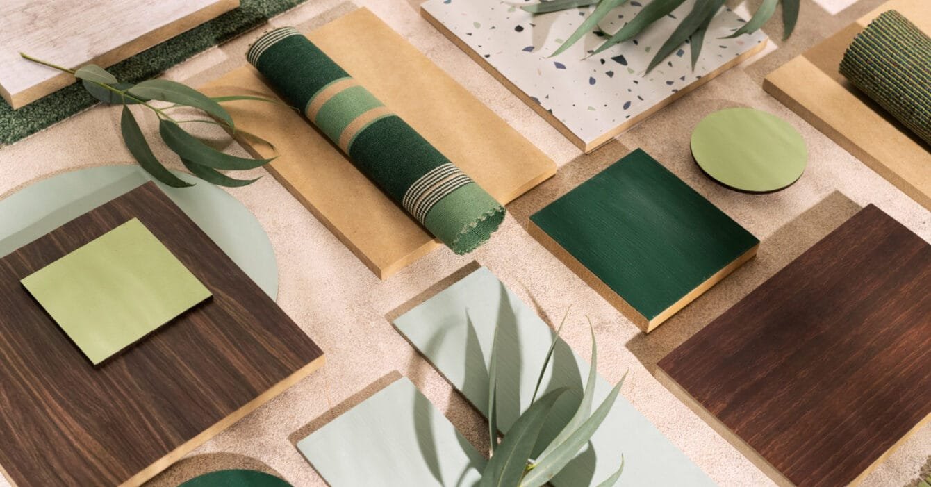 Indonesia Sustainable Materials Adoption: Flat lay of interior design materials in green and brown tones with fabric samples and leaves.